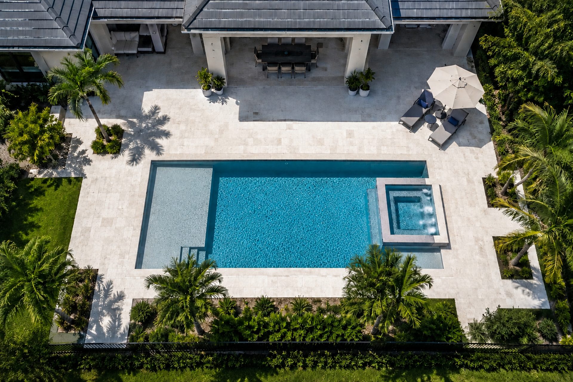 Aerial view of a rectangular swimming pool with a spa and travertine paver deck